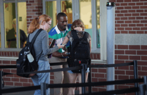 Teacher monitoring students as they pass through a weapon detection system at school entrance